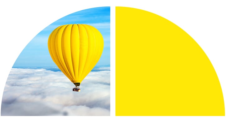 Yellow hot air balloon floats above the clowds against a blue sky.