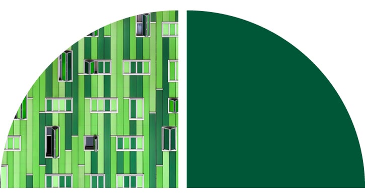 A building facade with vertical green panels and multiple open windows.