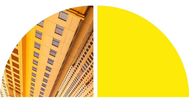 A semi-circle split into two halves: the left side features a yellow-tinted upward view of a multi-windowed building, while the right side is solid yellow.