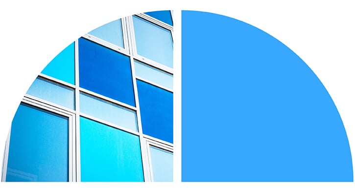 Abstract blue-toned glass building facade with geometric panes and curved shapes.